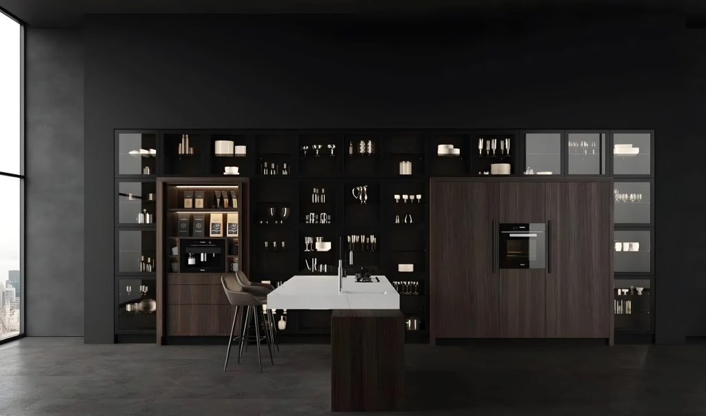 Modern luxury kitchen with dark cabinets, a center island featuring a built-in stovetop, bar stools, and various kitchen appliances and utensils on display shelves.