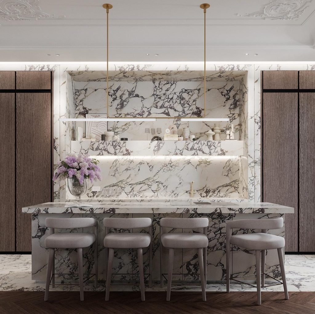 A modern kitchen features marble-patterned countertops and backsplashes, four gray bar stools, and two pendant lights. A vase with purple flowers sits on the island counter, epitomizing the elegance of bespoke luxury kitchens.