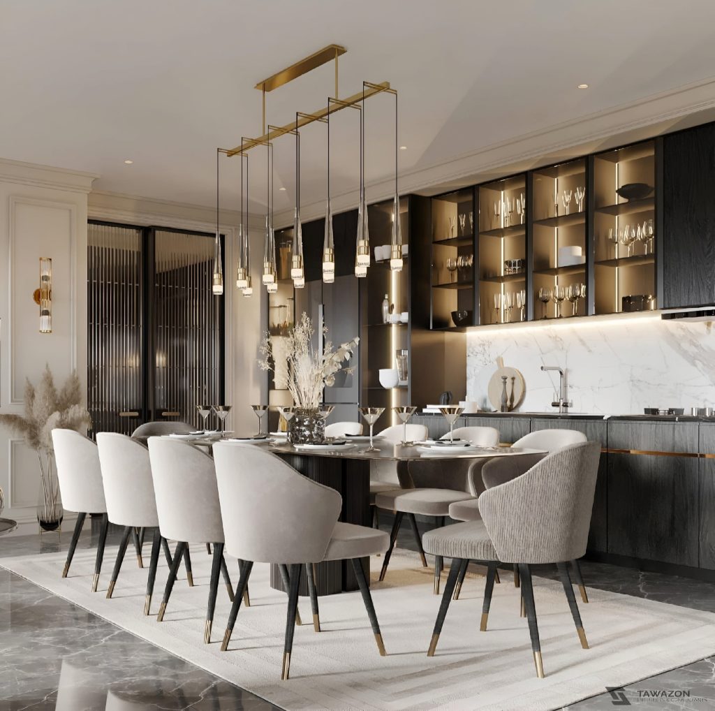 A modern dining room with a long wooden table, eight grey upholstered chairs, a gold and glass chandelier, and a backlit shelf displaying glassware against a marble and dark wood setting. This space exemplifies the refined elegance seen in bespoke luxury kitchens.