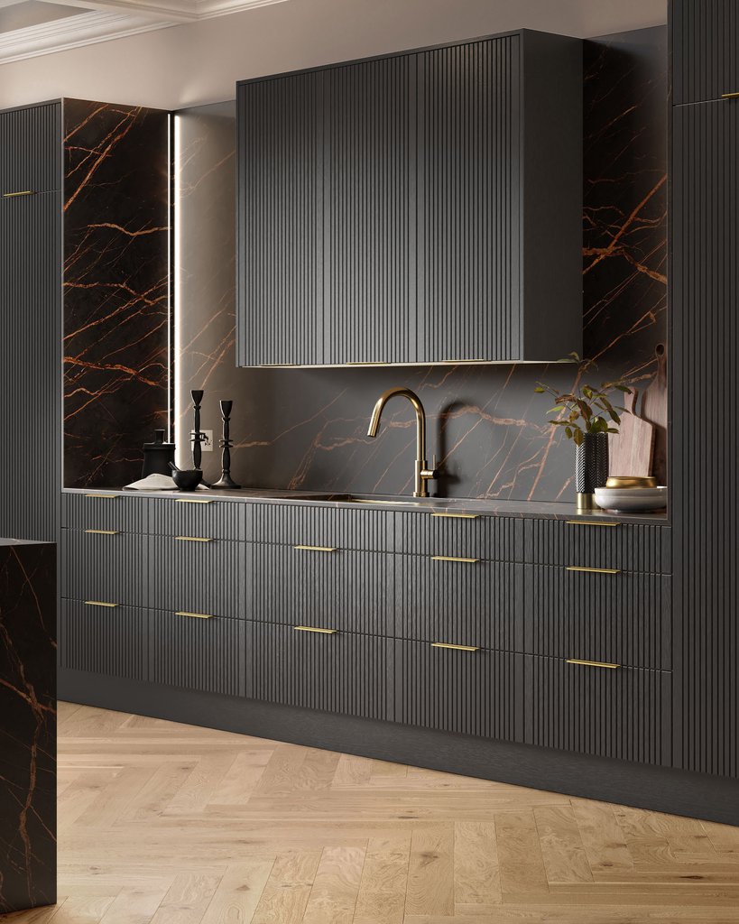 Modern kitchen with dark ribbed cabinets, a marble backsplash, and a gold faucet. Decor includes candlesticks and a plant on the countertop. Wood-patterned floor underfoot.